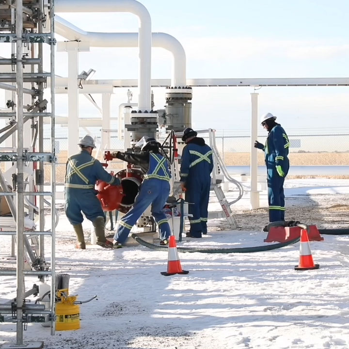 A group of four technicians prepare to launch a tool inside the pipeline at a pipeline station during winter weather.