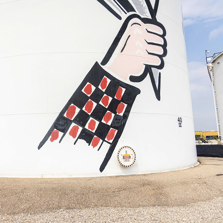 Fuel tank with painting of arm holding up a hat on it.