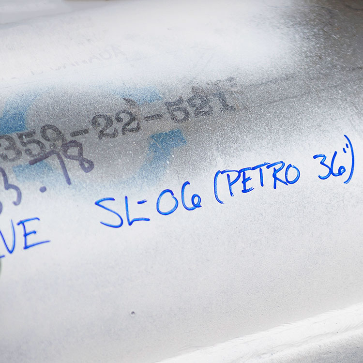 Writing in blue marker on a white pipeline sleeve.