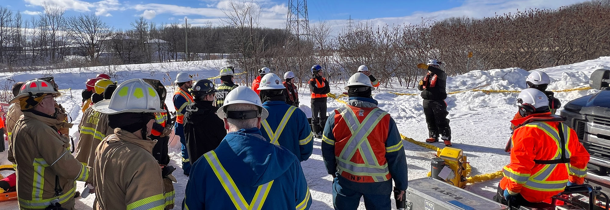 A group of first responders and pipeline technicians are briefed before deploying boom over a frozen river during a training exercise in Quebec.